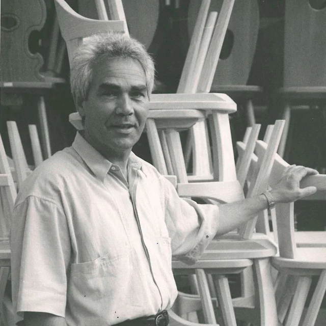 Martin Plank Sr. among stacked wooden farmhouse chairs
