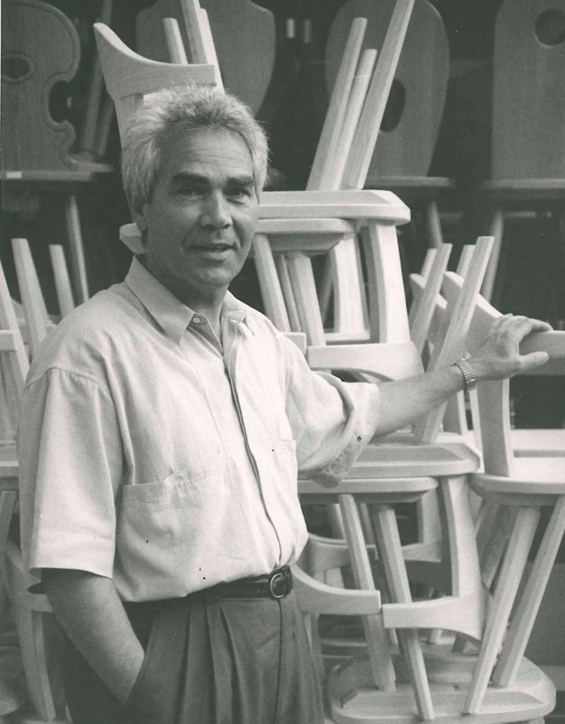 Martin Plank Sr. among stacked wooden farmhouse chairs